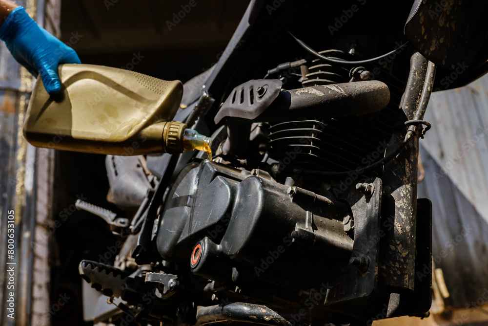 Fototapeta premium pouring new motor oil into a motorcycle engine 
