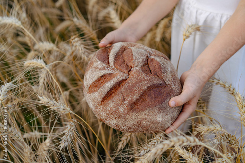 Little beautiful blonde girl with rye bread in a field of ears of rye