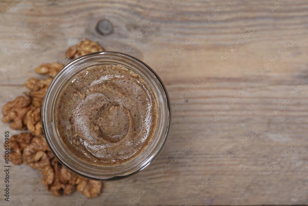 Tasty walnut nut paste in jar on wooden table, top view. Space for text Tasty walnut nut paste in jar on wooden table, top view. Space for text