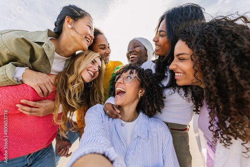 Diverse group of happy young best female friends having fun together outdoors. International youth community concept with multiracial girls from different cultures bonding at city street. photo