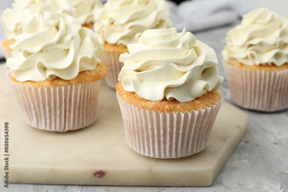 Tasty cupcakes with vanilla cream on grey table, closeup Tasty cupcakes with vanilla cream on grey table, closeup