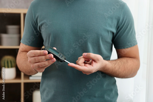 Diabetes test. Man checking blood sugar level with glucometer at home, closeup