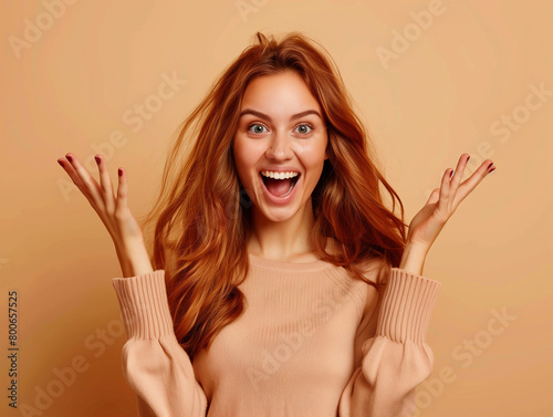 A woman with red hair is smiling and waving her hands in the air photo