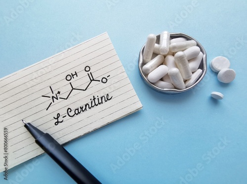 Structural chemical formula of L-carnitine with white tablets. L-carnitine is an amino acid produced by the body, also found in supplements, helps the body turn fat into energy. Dietary supplements. photo