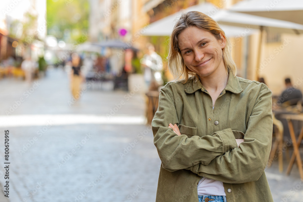 Fototapeta premium Portrait of happy young woman face smiling friendly glad expression looking at camera resting relaxation feel satisfied good news outdoors. Pretty blond adult girl tourist traveler on city street.