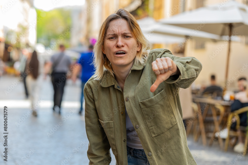 Dislike. Upset young woman showing thumbs down sign gesture, expressing discontent, disapproval, dissatisfied bad work, mistake outdoors. Displeased tourist girl on urban city street. Town lifestyles. Dislike. Upset young woman showing thumbs down sign gesture, expressing discontent, disapproval, dissatisfied bad work, mistake outdoors. Displeased tourist girl on urban city street. Town lifestyles.
