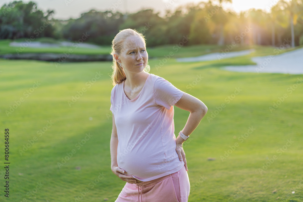 Expectant woman experiences back pain outdoors, seeking relief and comfort during pregnancy with a gentle outdoor stretch or rest Expectant woman experiences back pain outdoors, seeking relief and comfort during pregnancy with a gentle outdoor stretch or rest