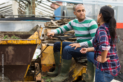 Farm workers have a dialogue next to the tractor photo