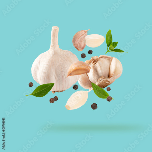Garlic clove with parsley leaves and pepper
falling on tranquil background.