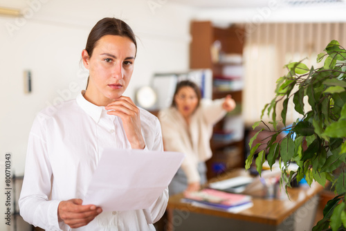 Angry woman boss firing upset young female employee in office photo