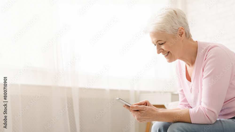 Cheerful senior woman using her smartphone at home Cheerful senior woman using her smartphone at home