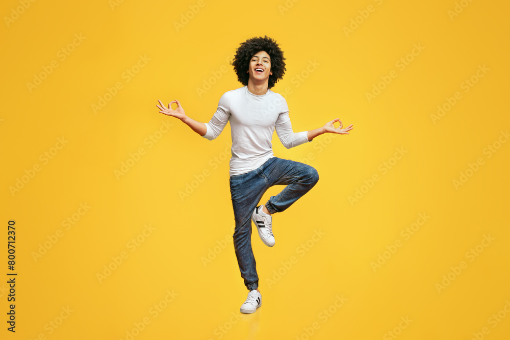 Fototapeta premium Funny young man sitting in mid air, balancing on one leg
