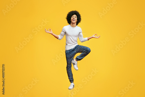 Funny young man sitting in mid air, balancing on one leg photo
