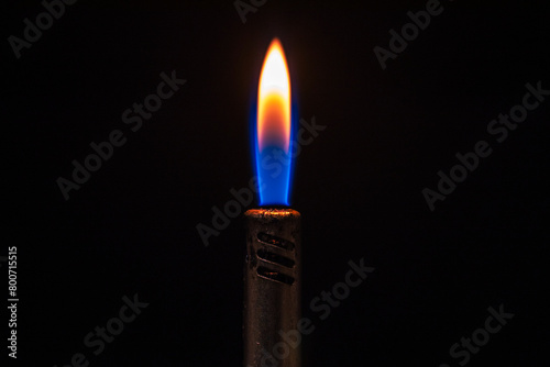 Detalle de la llama encendida de un mechero de gas azul en la oscuridad photo