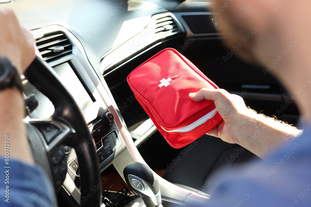 Obraz premium Man with first aid kit inside car, closeup