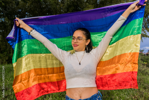 Mujer adulta media sosteniendo una bandera del arco iris al aire libre  photo