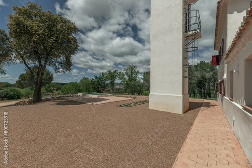 A long perimeter hallway in a country house with white facades and terracotta floors on a day with bright skies and passing clouds and great scenery photo