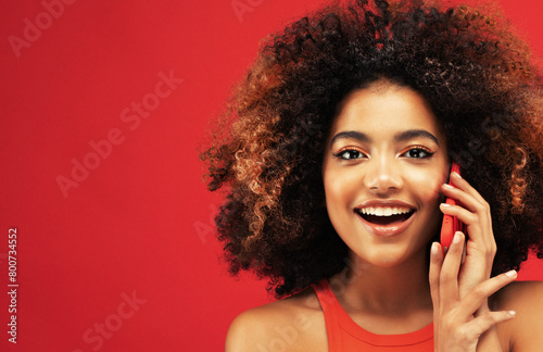 Portrait of inspired dreamy american young surprised woman use her smartphone over red background
