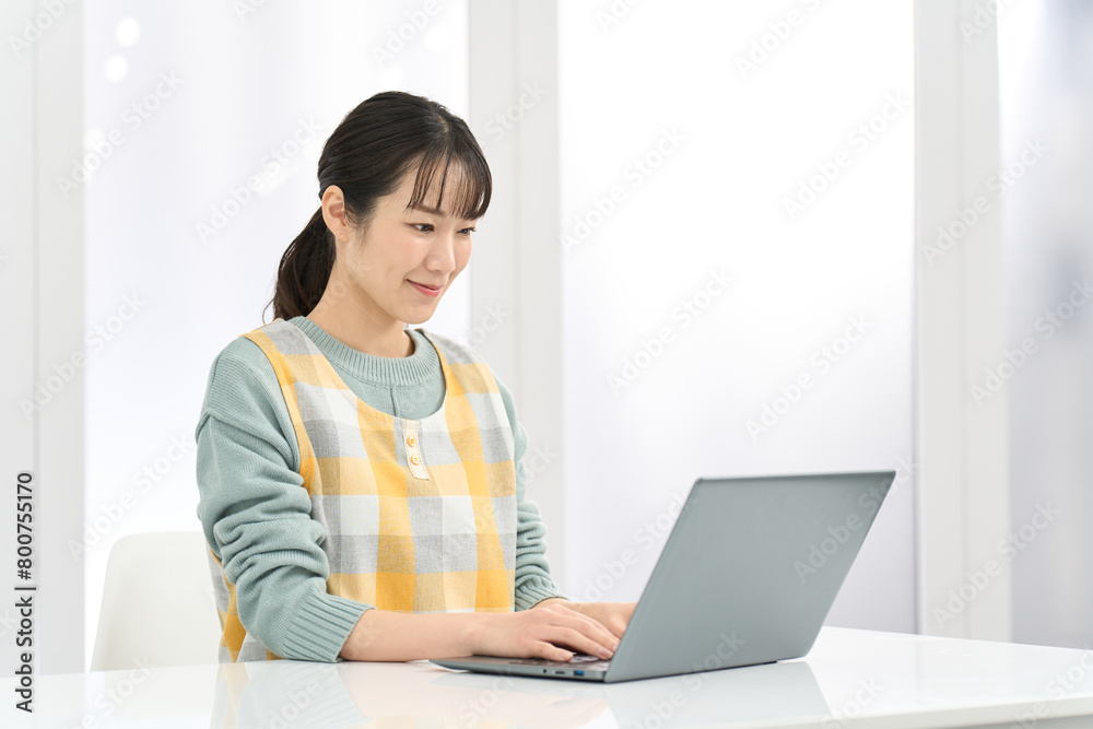 パソコン作業をするエプロンを着た女性