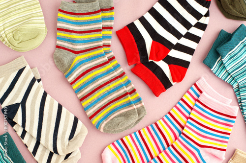 Colorful socks on a pink background. A lot of socks are scattered on the surface. Clothing in the form of socks.