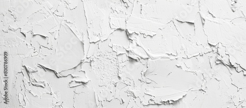Close-up view of white paint flaking and peeling off a wall surface, revealing layers beneath