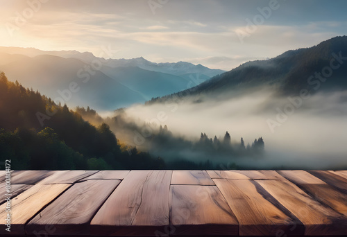 Wooden table overlooking a misty mountain landscape at sunrise, with layers of hills and light filtering through the trees.