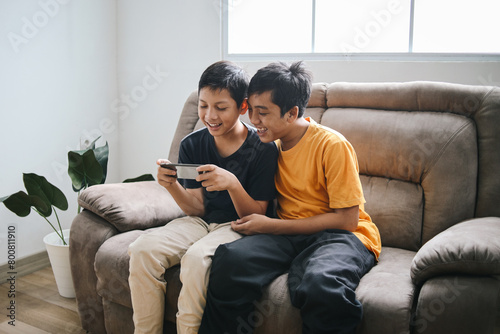Young Two Boys Friends Enjoy Playing Online Games on Smartphone at Home 