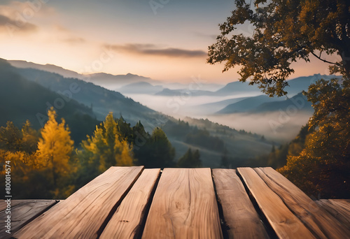 Wooden table overlooking a misty mountain landscape at sunrise, with trees in autumn colors.