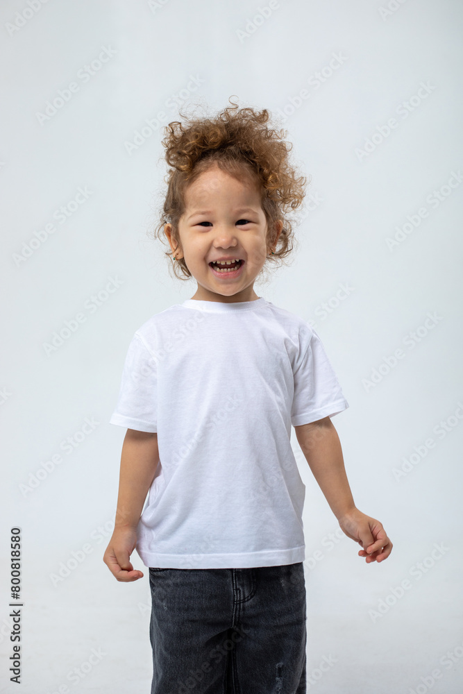 Curly mischievous girl, rejoicing, smiling, looking at the camera, in dark jeans posing on a white background Curly mischievous girl, rejoicing, smiling, looking at the camera, in dark jeans posing on a white background