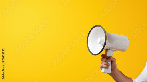 Holding megaphone in hand on yellow background.