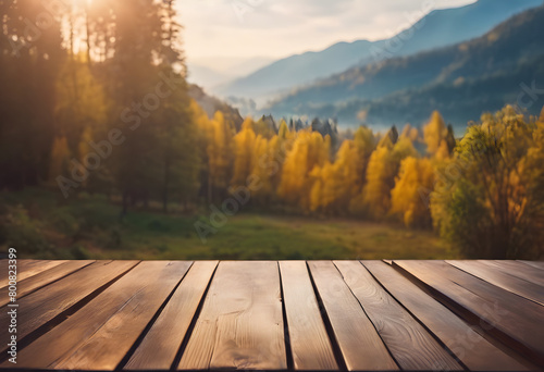 Wooden table overlooking a scenic autumn landscape with golden trees and mountains in the background.