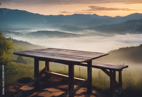A serene mountain view with a wooden table overlooking layers of misty hills at sunrise.