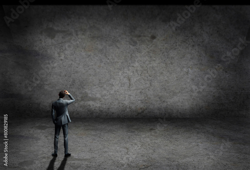 man in suit inside an empty room with concrete grey wall and floor