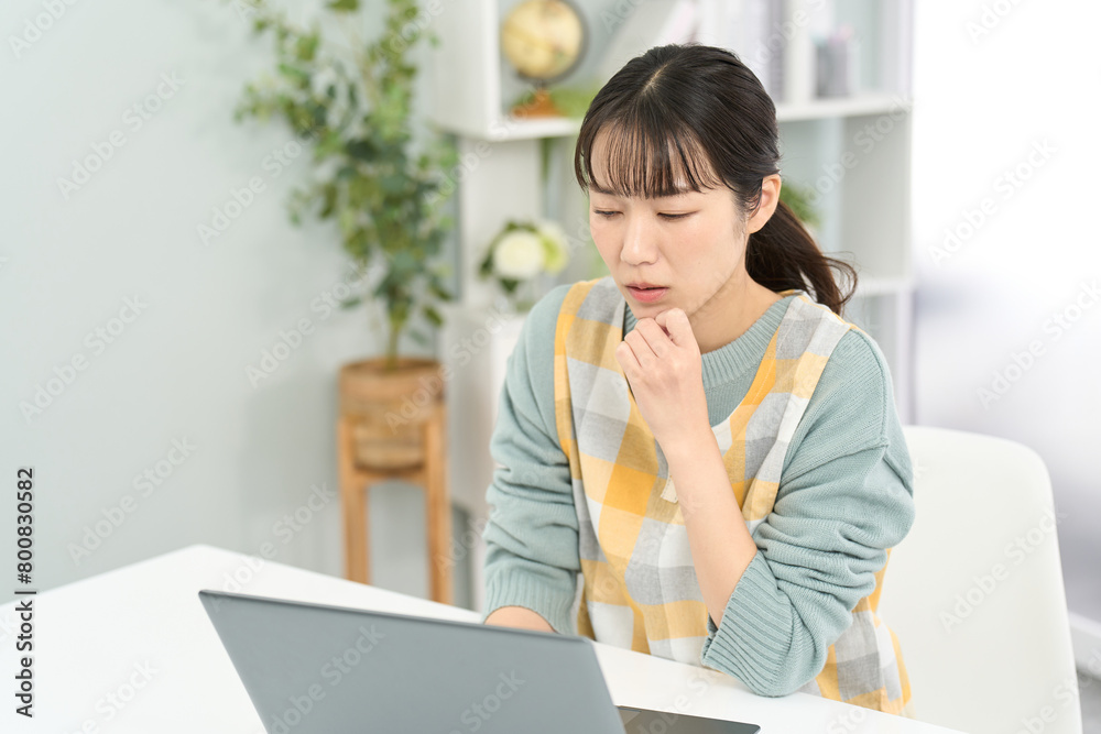 パソコン作業で悩むエプロンを着た女性