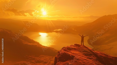 A person standing on a rock outcropping looking at a sunset over a canyon. The sky is orange and the rock formations are dark.