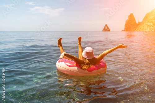 Summer vacation woman in hat floats on an inflatable donut mattress. Happy woman relaxing and enjoying family summer travel holidays travel on the sea.