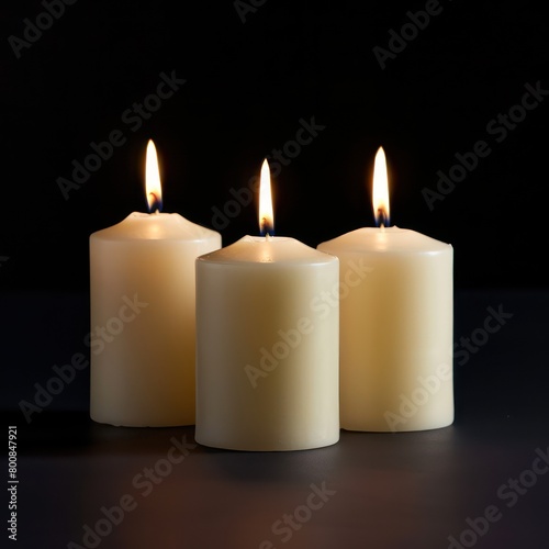 Three flickering candles illuminate the darkness, casting a warm glow against the black background, creating a serene and enchanting ambiance