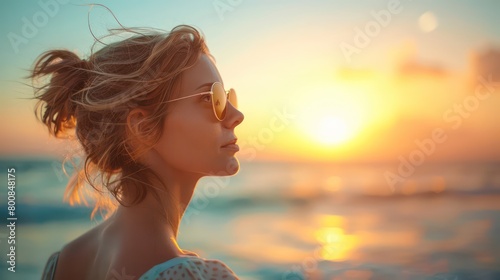 Gracefully adorned in sunglasses, a 40-year-old woman savors the beach's tranquility, her gaze fixed on the sun's radiant embrace © beatriz