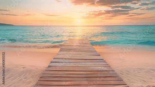 Beautiful sandy beach with a wooden path going to the sea at sunset