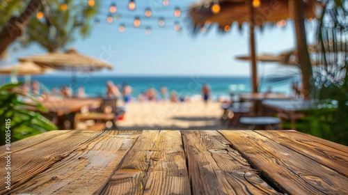 An empty wooden table with a blurred beach party in the background, setting the stage for summer gatherings.
