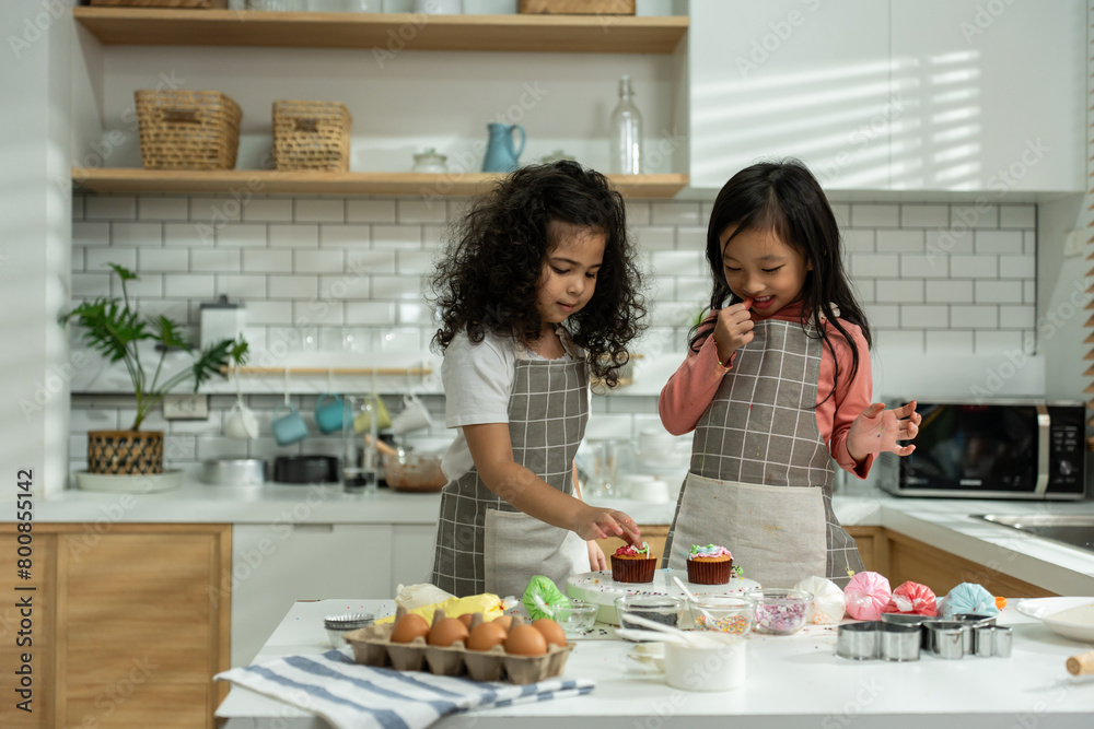 Two Asian adorable children sibling making a cake in kitchen at house. 