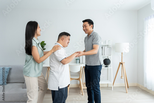 Asian attractive family dancing with young son in living room in house. 