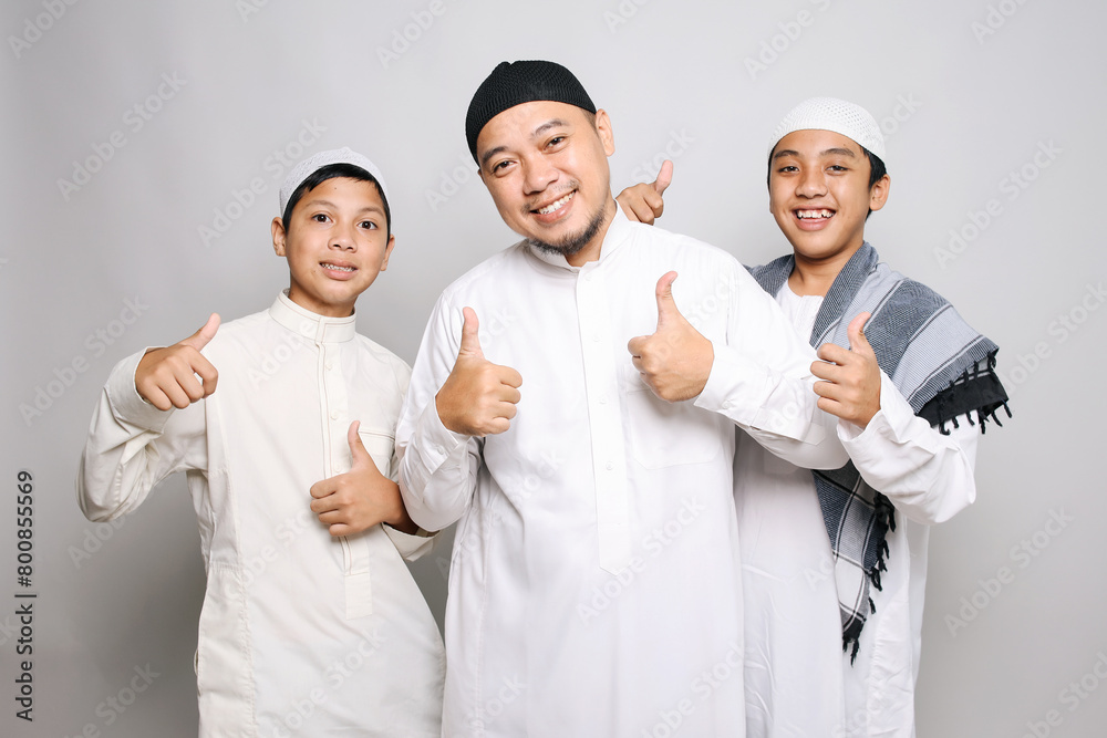 Cheerful muslim dad and children in white robe showing thumbs up Cheerful muslim dad and children in white robe showing thumbs up