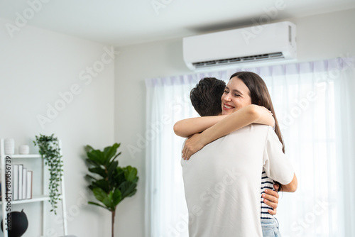 Caucasian young man and woman hugging each other in living room at home. 
