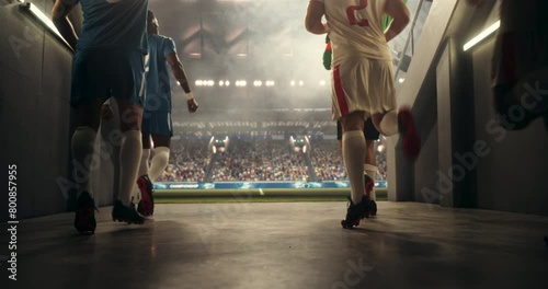 Two Multiethnic Football Teams Walking Out of the Tunnel onto the Sports Stadium Field. Opposing Footballers Entering a Crowded Arena Full of Soccer Spectators. Warm Color Grading photo