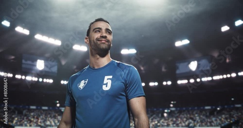 Soccer Player Presentation: Handsome Middle Eastern Footballer Posing, Looking at Camera and Smiling. Confident Happy Young Man in Blue Uniform Getting Pumped Up Before a Tournament Match photo