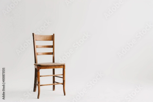 A minimalistic ladderback chair against a solid white surface.