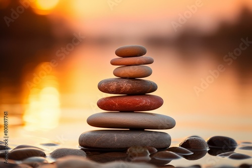 Stones stacked on each other on a beach with the sunset in the background