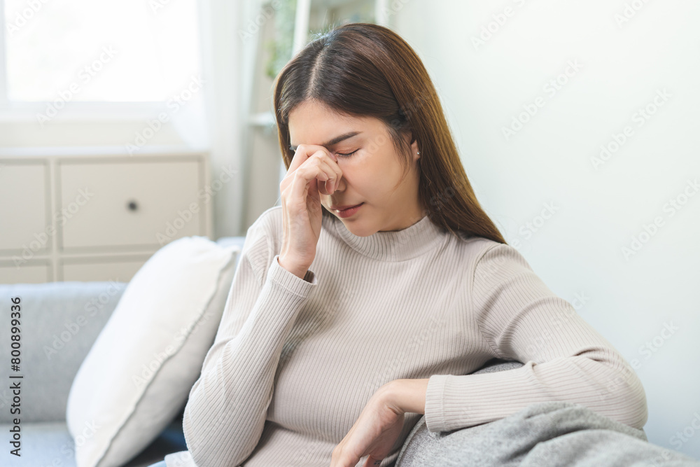 Depressed anxiety asian young woman, girl frustrated closed eyes, touching face suffering stressed, sick, tired, crisis sitting on sofa from headache, migraine pain tension problem health care concept Depressed anxiety asian young woman, girl frustrated closed eyes, touching face suffering stressed, sick, tired, crisis sitting on sofa from headache, migraine pain tension problem health care concept