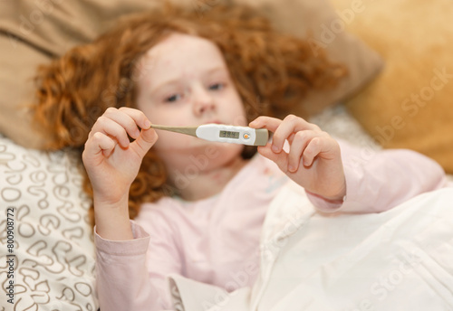 Close up, little girl holding a thermometer. Chickenpox virus.